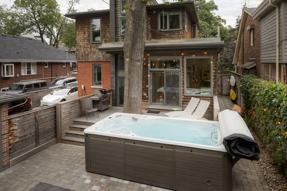 swim spa in a backyard setting, surrounded by trees and a fence