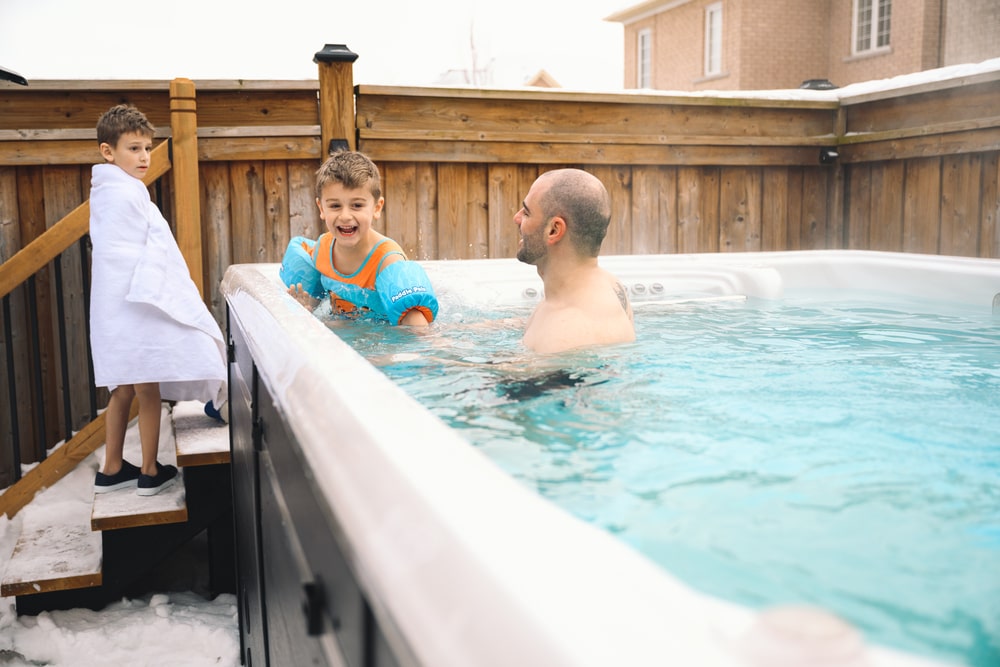 kids is having fun with their father in a swim spa in winter