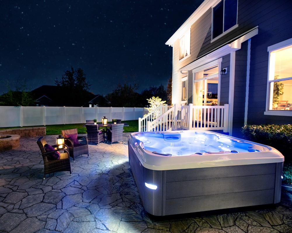 X-Series hot tub night installation in a backyard of a house