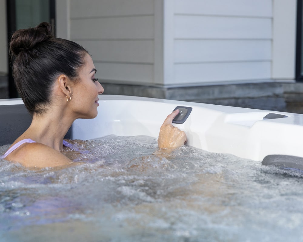 A person in a bubbling hot tub while using control panel