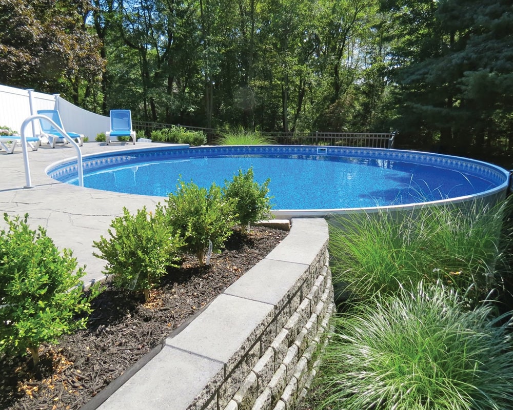 semi in-ground pool in a backyard surrounded by greenary